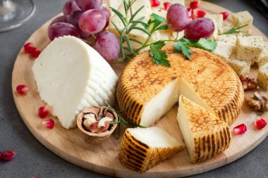 Peynir tabağı ile çeşitli peynirler, üzüm, fındık gri taş zemin, kopya alanı üzerinde. İtalyan peynir ve meyve tabağı.