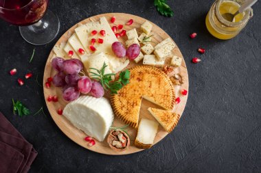 Peynir tabağı ile çeşitli peynirler, üzüm, fındık siyah arka plan, kopya alanı üzerinde. Bal ve şarap ile İtalyan peynir ve meyve tabağı.