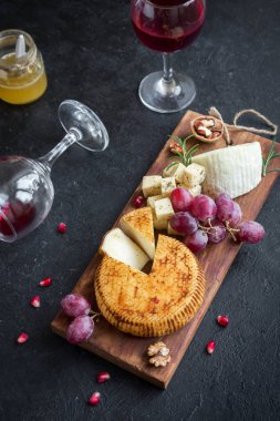 Peynir tabağı ile çeşitli peynirler, üzüm, fındık siyah arka plan, kopya alanı üzerinde. Bal ve şarap ile İtalyan peynir ve meyve tabağı.