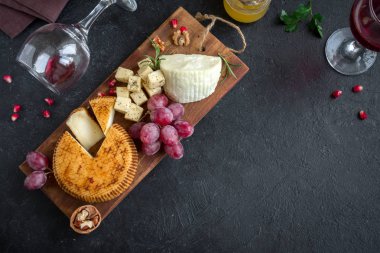 Peynir tabağı ile çeşitli peynirler, üzüm, fındık siyah arka plan, kopya alanı üzerinde. Bal ve şarap ile İtalyan peynir ve meyve tabağı.