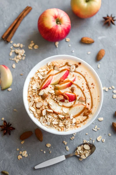 Apple Pie Smoothie Bowl. Breakfast smoothie bowl with apples, cinnamon, almond milk, oat granola and spices, top view.