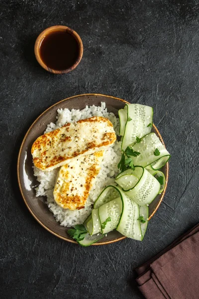 Pirinç ve salatalık salatası siyah arka plan, tofu biftek alanı kopyalayın. Kavrulmuş kızarmış tofu biftek ile sağlıklı vegan vejetaryen yemek yemek.