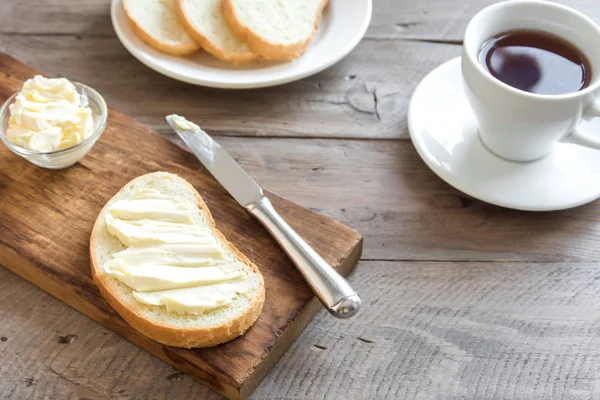Rustik ahşap arka plan kopya alanı ile kahve fincan ile kahvaltıda ekmek ve tereyağı. Sabah kahvaltı kahve, tereyağı ve tost ile.