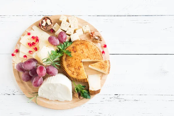 Peynir tabağı ile çeşitli peynirler, üzüm, fındık Beyaz ahşap arka plan, kopya alanı üzerinde. İtalyan peynir ve meyve tabağı.