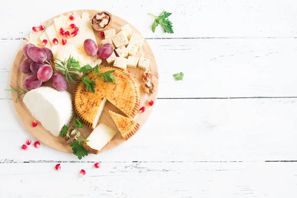 Peynir tabağı ile çeşitli peynirler, üzüm, fındık Beyaz ahşap arka plan, kopya alanı üzerinde. İtalyan peynir ve meyve tabağı.