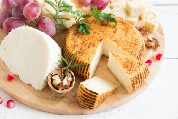 Peynir tabağı ile çeşitli peynirler, üzüm, fındık Beyaz ahşap arka plan, kopya alanı üzerinde. İtalyan peynir ve meyve tabağı.
