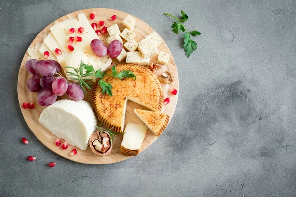 Peynir tabağı ile çeşitli peynirler, üzüm, fındık gri taş zemin, kopya alanı üzerinde. İtalyan peynir ve meyve tabağı.
