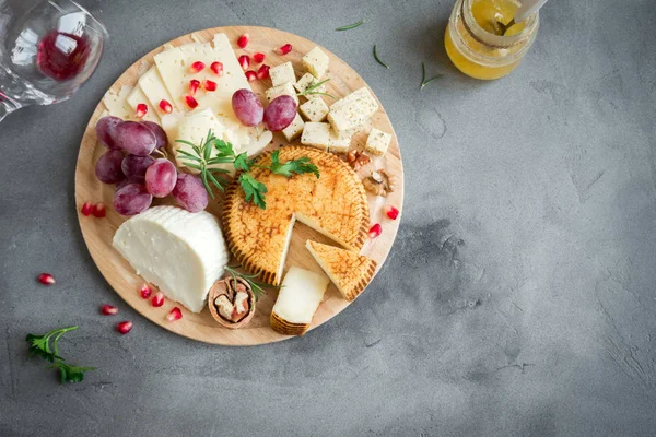 Peynir tabağı ile çeşitli peynirler, üzüm, fındık gri taş zemin, kopya alanı üzerinde. İtalyan peynir ve meyve tabağı.