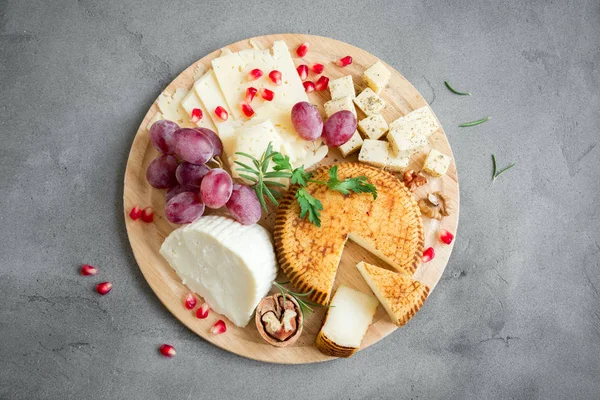 Peynir tabağı ile çeşitli peynirler, üzüm, fındık gri taş zemin, kopya alanı üzerinde. İtalyan peynir ve meyve tabağı.