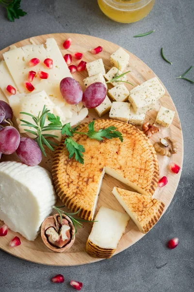 Peynir tabağı ile çeşitli peynirler, üzüm, fındık gri taş zemin, kopya alanı üzerinde. İtalyan peynir ve meyve tabağı.