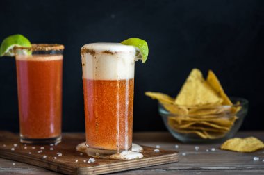 Michelada (Meksika kanlı bira) Spisy jant ve domates suyu ile Limes ve Nacho patates kızartması ile servis. Yaz alkol kokteyl Michelada.
