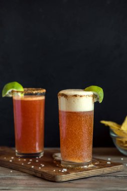 Michelada (Meksika kanlı bira) Spisy jant ve domates suyu ile Limes ve Nacho patates kızartması ile servis. Yaz alkol kokteyl Michelada.