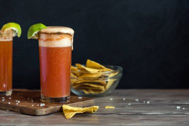 Michelada (Meksika kanlı bira) Spisy jant ve domates suyu ile Limes ve Nacho patates kızartması ile servis. Yaz alkol kokteyl Michelada.