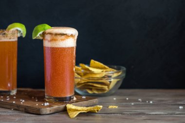Michelada (Meksika kanlı bira) Spisy jant ve domates suyu ile Limes ve Nacho patates kızartması ile servis. Yaz alkol kokteyl Michelada.