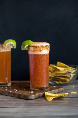 Michelada (Meksika kanlı bira) Spisy jant ve domates suyu ile Limes ve Nacho patates kızartması ile servis. Yaz alkol kokteyl Michelada.