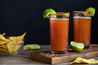 Michelada (Meksika kanlı bira) Spisy jant ve domates suyu ile Limes ve Nacho patates kızartması ile servis. Yaz alkol kokteyl Michelada.