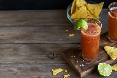 Michelada (Meksika kanlı bira) Spisy jant ve domates suyu ile Limes ve Nacho patates kızartması ile servis. Yaz alkol kokteyl Michelada.