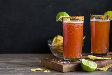 Michelada (Meksika kanlı bira) Spisy jant ve domates suyu ile Limes ve Nacho patates kızartması ile servis. Yaz alkol kokteyl Michelada.