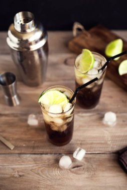 ROM ve cola Cuba Libre içkiyle kireç ve buz üzerinde rustik ahşap masa