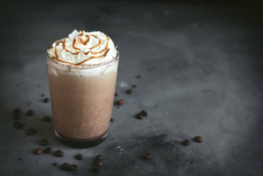 Krem şanti ve koyu arka plan, karamel ile soğuk Frappe kahve (frappuccino) kopyalama alanı.
