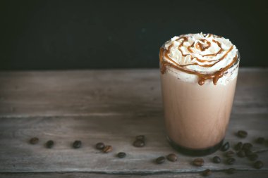 Krem şanti ve koyu arka plan, karamel ile soğuk Frappe kahve (frappuccino) kopyalama alanı.