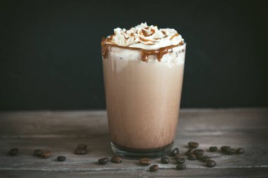 Krem şanti ve koyu arka plan, karamel ile soğuk Frappe kahve (frappuccino) kopyalama alanı.