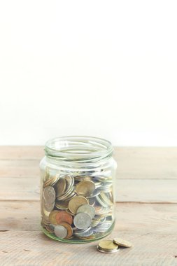 Cam kavanoz para çıktı. Para tasarruf kavramı. Ahşap masa, kopya alanı üzerinde çeşitli paralar ile jar.