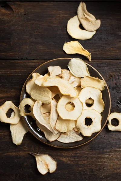 Koyu ahşap arka plan, kopya alanı çeşitli meyve yongaları. Karışık kurutulmuş elma, armut, kavun, mango meyve cips - sağlıklı vegan snack.