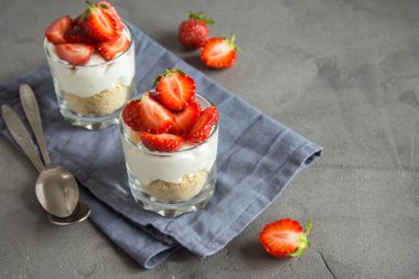 Çilekli cheesecake taze çilek ve gri beton zemin üzerine krem peynir ile gözlük. Sağlıklı ev yapımı mini tatlı.