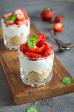 Çilekli cheesecake taze çilek ve ahşap zemin üzerine krem peynir ile gözlük. Sağlıklı ev yapımı potrion tatlı.