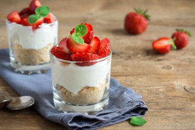 Çilekli pasta ister taze çilek ve ahşap zemin üzerine krem peynir ile bardaklarda mini tatlı. Sağlıklı ev yapımı potrion tatlı.