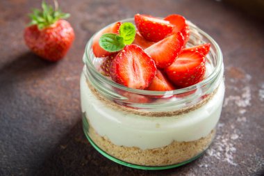 Çilekli cheesecake taze çilek ve krem peynir koyu arka plan üzerinde cam kavanoza. Sağlıklı ev yapımı tatlı.