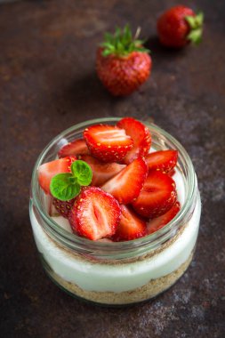 Çilekli cheesecake taze çilek ve krem peynir koyu arka plan üzerinde cam kavanoza. Sağlıklı ev yapımı tatlı.