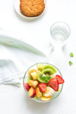Sağlıklı kahvaltı veya aperatif için kase meyve salatası. Ham vejetaryen fitness gıda ve yaşam tarzı kavramı, beyaz arka plan kopya alanı ile diyet.