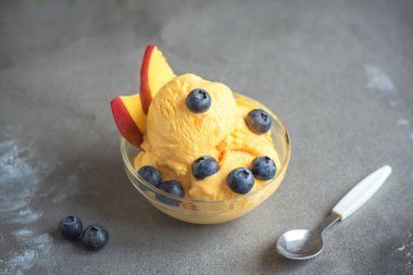 Mango Dondurma veya sorbe kasede yaban mersini ile. Ev yapımı meyve mango dondurma gri arka plan, kopya alanı üzerinde.