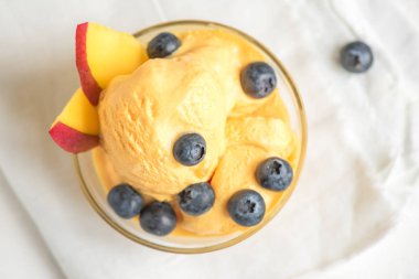 Mango Dondurma veya sorbe kasede yaban mersini ile. Ev yapımı meyve mango dondurma beyaz arka planda, üstten görünüm.