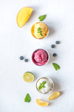 Üç çeşitli meyve ve çilek dondurma beyaz arka planda, kopya alanı. Dondurulmuş yoğurt veya dondurma ile limon, mango, yaban mersini - sağlıklı yaz tatlı.