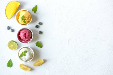 Üç çeşitli meyve ve çilek dondurma beyaz arka planda, kopya alanı. Dondurulmuş yoğurt veya dondurma ile limon, mango, yaban mersini - sağlıklı yaz tatlı.