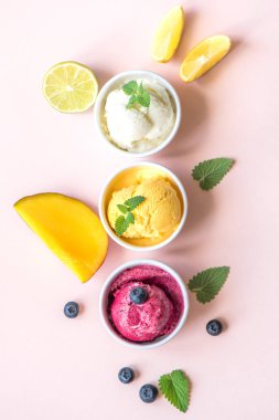 Üç çeşitli meyve ve çilek dondurma pembe arka plan, kopya alanı üzerinde. Dondurulmuş yoğurt veya dondurma ile limon, mango, yaban mersini - sağlıklı yaz tatlı.