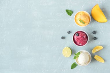 Üç çeşitli meyve ve çilek dondurma mavi arka plan, kopya alanı üzerinde. Dondurulmuş yoğurt veya dondurma ile limon, mango, yaban mersini - sağlıklı yaz tatlı.