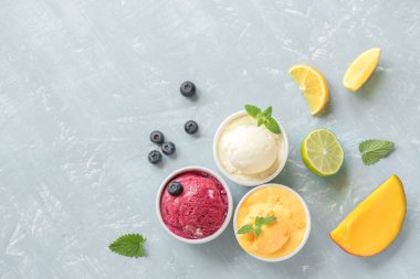 Üç çeşitli meyve ve çilek dondurma mavi arka plan, kopya alanı üzerinde. Dondurulmuş yoğurt veya dondurma ile limon, mango, yaban mersini - sağlıklı yaz tatlı.