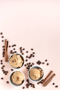 Kahveli dondurma pembe pastel arka planda, üstten görünüm alanı kopyalayın. Kahve çekirdekleri ile dondurulmuş kahve gelato dondurma ve tarçın - sağlıklı tatlı yaz.
