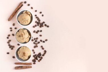 Kahveli dondurma pembe pastel arka planda, üstten görünüm alanı kopyalayın. Kahve çekirdekleri ile dondurulmuş kahve gelato dondurma ve tarçın - sağlıklı tatlı yaz.