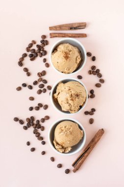 Kahveli dondurma pembe pastel arka planda, üstten görünüm alanı kopyalayın. Kahve çekirdekleri ile dondurulmuş kahve gelato dondurma ve tarçın - sağlıklı tatlı yaz.