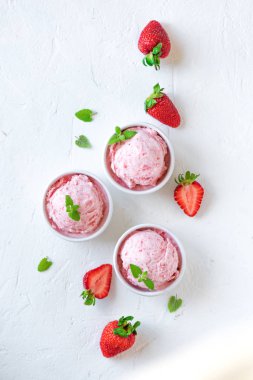 Çilekli dondurma ve beyaz arka planda, üstten görünüm taze çilek. Üç kâse çilekli dondurma, sağlıklı tatlı yaz.