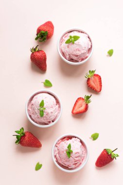 Çilekli dondurma ve pembe arka plan, üstten görünüm üzerinde taze çilek. Üç kâse çilekli dondurma, sağlıklı tatlı yaz.