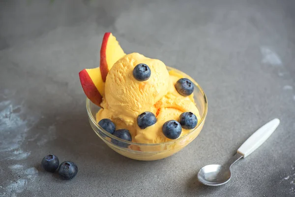 Mango Dondurma veya sorbe kasede yaban mersini ile. Ev yapımı meyve mango dondurma gri arka plan, kopya alanı üzerinde.