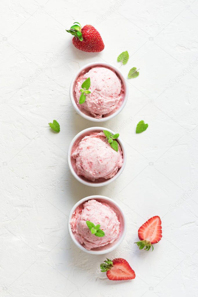 Strawberry ice cream and fresh strawberries on white background, top view. Three bowls of strawberry ice cream, healthy summer dessert.