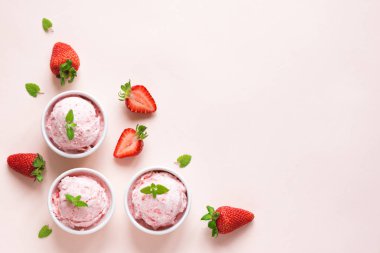 Çilekli dondurma ve pastel pembe kopya alanı üzerinde taze çilek. Üç kâse çilekli dondurma, sağlıklı tatlı yaz.