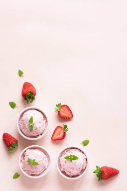 Çilekli dondurma ve pastel pembe kopya alanı üzerinde taze çilek. Üç kâse çilekli dondurma, sağlıklı tatlı yaz.